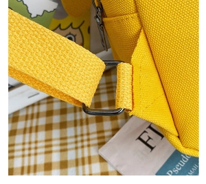 Close-up of yellow canvas backpack showing metal buckle detail and woven texture