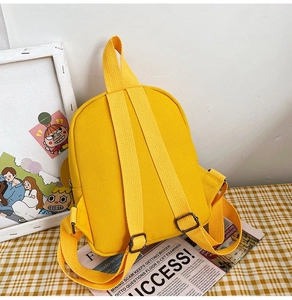 Top view of a mini yellow canvas backpack featuring adjustable straps and top handle
