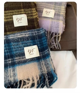 Detailed view of plaid wool-feel scarf with long fringe in green, purple, and blue colors