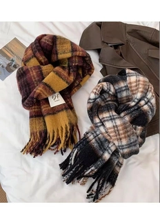Flat lay of plaid tassel scarves in warm brown and cool grey tones on white bedding