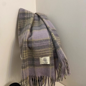 Detail of plaid tassel scarf in purple and tan featuring YF.BLOSSOM brand fabric label