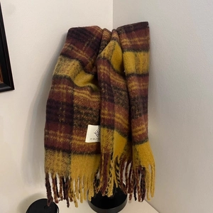 Detailed view of vintage plaid tassel scarf in brown and yellow with woven brand label