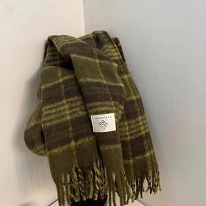 Detail of the woven brand label and fringe on the vintage plaid winter scarf