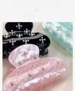 Close-up of three pearlescent acrylic hair claw clips with floral rhinestone patterns