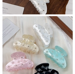 Detail of rhinestone flower patterns on marbled acrylic hair claw clips in pastel colors.