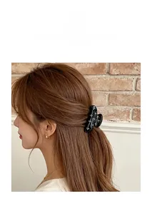 Acrylic hair claw clip with flower pattern and rhinestones shown on a model's hair