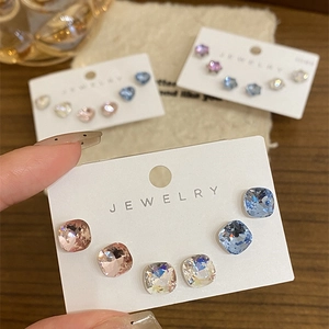 Macro shot of three pairs of sparkling geometric crystal stud earrings on white card