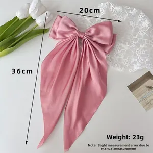 Detailed view of red satin bow hair clip measuring 20cm by 36cm with long ribbons