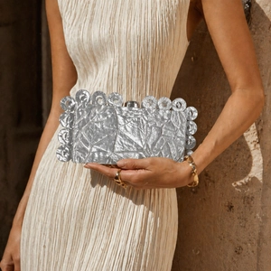 Elegant silver clutch bag with pleated metallic texture and stylish circular ring trim