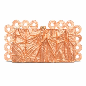 Macro view of rose gold textured acrylic clutch bag with artistic circular trim details