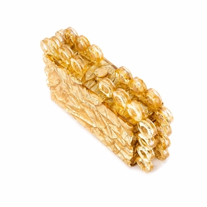 Macro detail of amber acrylic evening clutch bag with round metal closure and ring handle