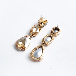Macro detail of tear-drop champagne crystal earrings with vintage gold metal backing
