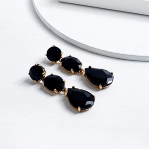 Detailed macro of gold drop earrings with triple-layered black crystal settings