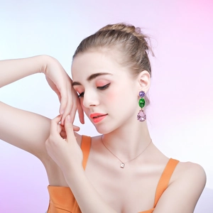 Close-up of model wearing vibrant teardrop crystal earrings in purple, green and pink