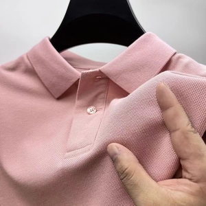 Close-up of pink piqué polo shirt fabric texture with classic lapel and light buttons