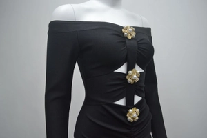 Détail de robe noire à épaules dénudées avec découpes et boucles en perles