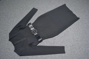 Détail d'une robe bandage noire à manches longues avec ceinture gaufrée et boucle en métal
