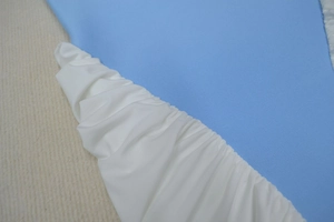 Close-up of sky blue ribbed fabric joined with fine white pleated material stitching