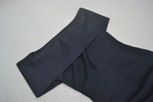 Close-up of black off-the-shoulder neckline detail with elegant textured woven fabric