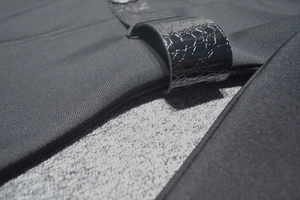 Détail d'une ceinture noire aspect crocodile sur une robe bandage à manches longues