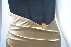 Détail de la taille avec plis en satin doré et décoration florale en cristal ambré