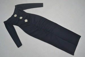 Détail des boutons perles dorés en fleur et du tissu froncé sur la robe noire