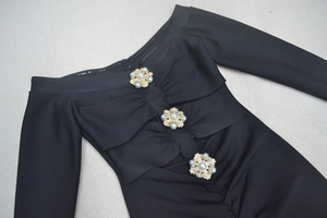 Détail des boutons en perles et cristaux sur une robe noire à épaules dénudées