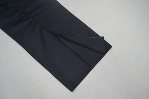 Détail d'une robe moulante noire avec fente latérale et texture froncée élégante
