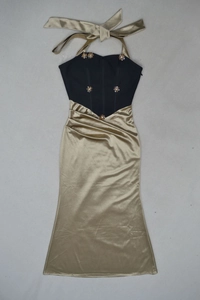 Détail de robe de soirée dos nu avec corset noir et jupe sirène en satin doré brillant