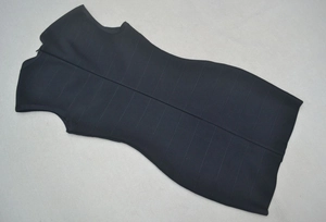 Détail d'une robe bandage noire avec coutures horizontales et fermeture éclair invisible
