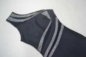 Détail de strass arc-en-ciel et maille serrée sur une robe noire à épaule dénudée