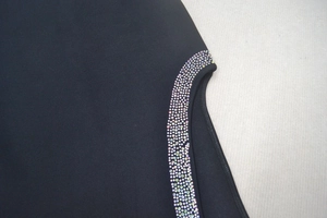 Détail macro de la découpe latérale avec strass colorés sur robe bandage noire chic