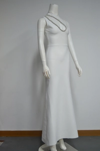 Détail d'une robe bandage blanche avec un col licou à grosse chaîne dorée chic