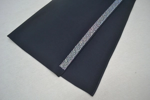 Détail d'une élégante robe bandage noire avec bandes verticales en strass et maille extensible