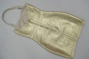 Détail de la robe bandage dorée avec texture verticale et fermeture éclair métallique