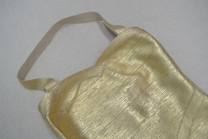 Détail de la robe licou dorée avec décolleté en V et tissu texturé à aspect métallique