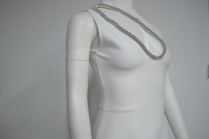 Détail d'une robe de soirée blanche sans manches avec bordure en cristaux argentés
