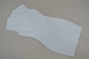 Détail de la texture du tissu bandage blanc et du col en V de cette robe moulante