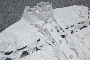 Détail du col en dentelle blanche et boutons de perles élégants sur une barboteuse ajustée