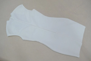 Détail à plat d'une robe bandage blanche sans manches avec col montant et zip au dos