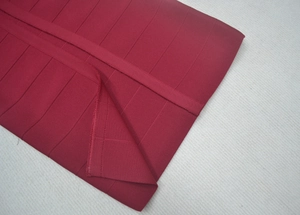 Dettaglio del tessuto elasticizzato rosso scuro dell'abito con cuciture a vista