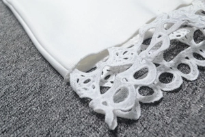 Gros plan d'un vêtement blanc avec broderie ajourée complexe et détails au crochet