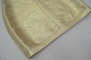 Détail de la robe bandage dorée montrant la texture côtelée métallique du tissu
