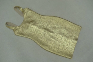 Detail of metallic gold bandage dress showing vertical silk texture and luxury fabric