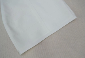 Gros plan détaillé de l'ourlet de la robe bandage blanche montrant le tissu élastique