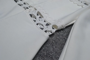 Détail de la dentelle blanche ajourée et broderie sur la manche de la combinaison
