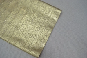 Gros plan sur un tissu doré métallisé avec texture brossée verticale et éclat brillant