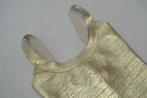 Detail of gold metallic fabric texture and elastic shoulder strap on a party dress