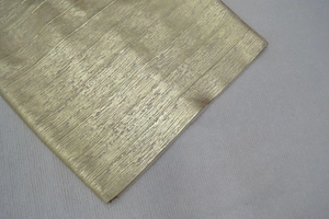 Macro shot of gold metallic fabric texture showing vertical brushed pattern on dress