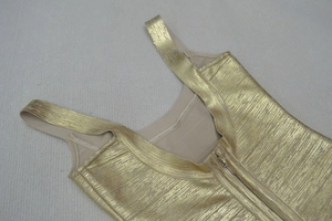 Detailed close-up of golden metallic bandage dress fabric showing texture and stitching